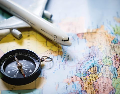 selective focus of miniature tourist on compass over map with plastic toy airplane,abstract background to travel concept.